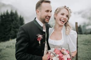 Lächelndes Brautpaar bei Hochzeit im Grünen, emotionaler Moment in Tirol, Hochzeitsfotograf aus Leidenschaft.