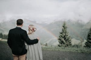 Naturpaar beim Hochzeitsfotografieren mit Bergpanorama und Regenbogen in Tirol, Österreich.