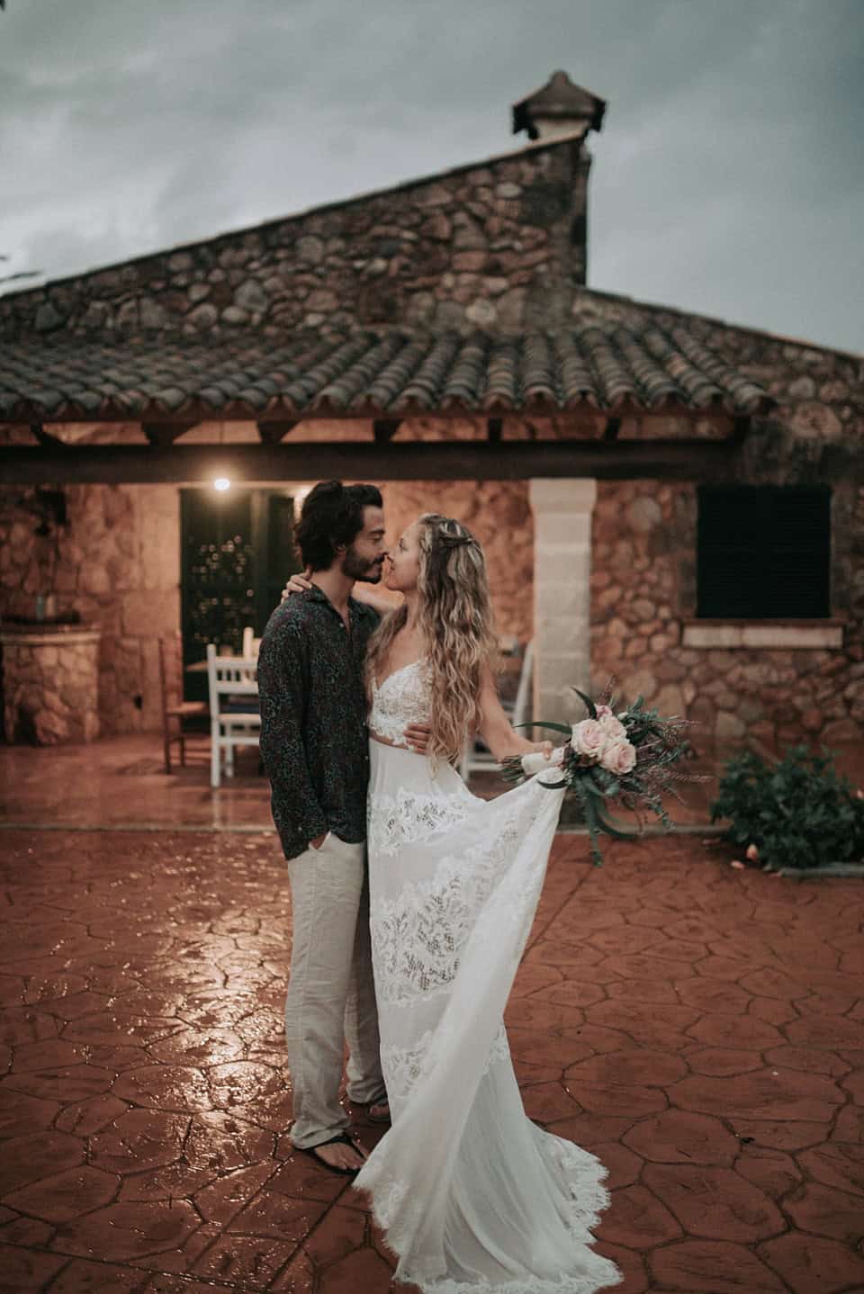 Romantisches Brautpaar bei Sonnenuntergang auf terrakottafarbenem Hof in Tirol, Österreich.