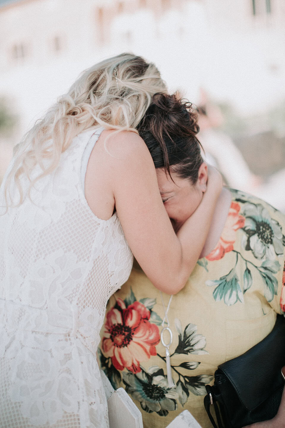 Lächelnde Frauen umarmen sich bei einer Hochzeit, emotionale Momente zwischen Braut und Gast.