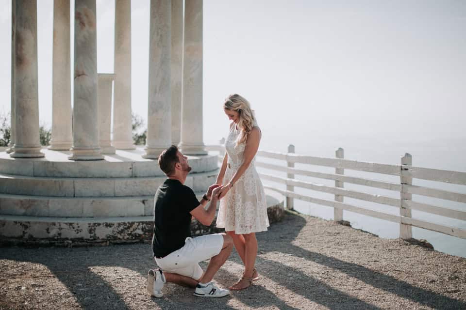 Verlobung am Meer auf historischen Säulen, romantischer Heiratsantrag am Strand.