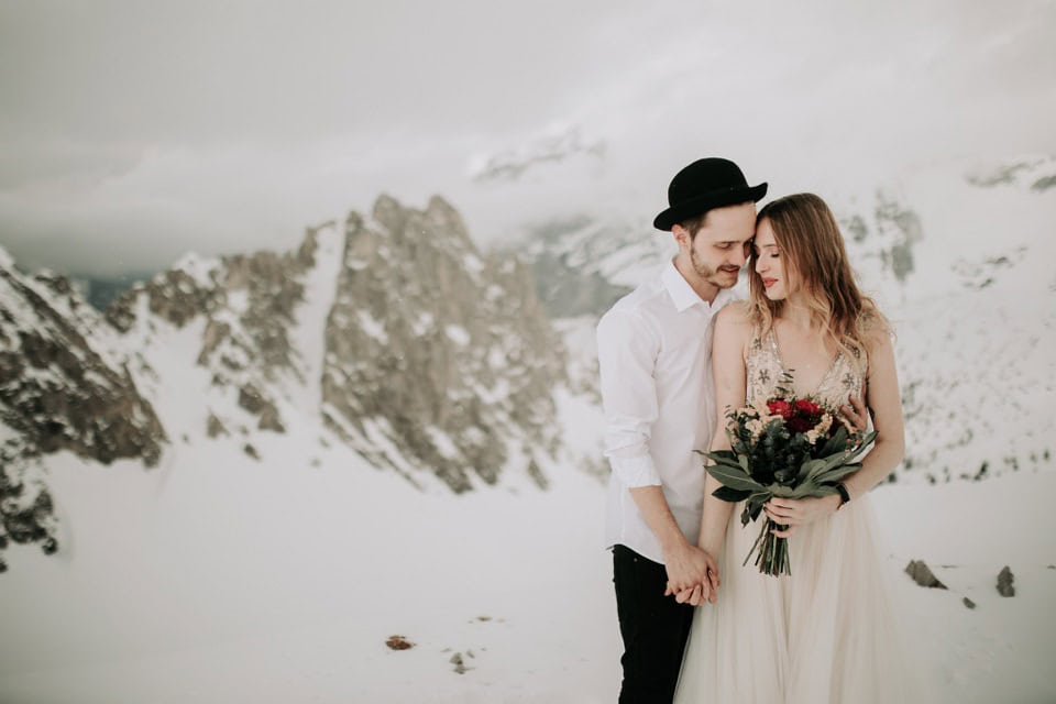 Romantisches Hochzeitsfoto in verschneiter Berglandschaft mit verliebtem Paar in Tirol, Österreich.