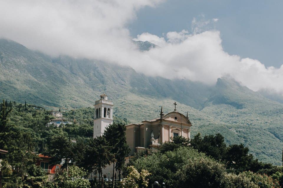 Bergdorf mit Kirche im Tiroler Alpenpanorama, Wolken über den Gipfeln.