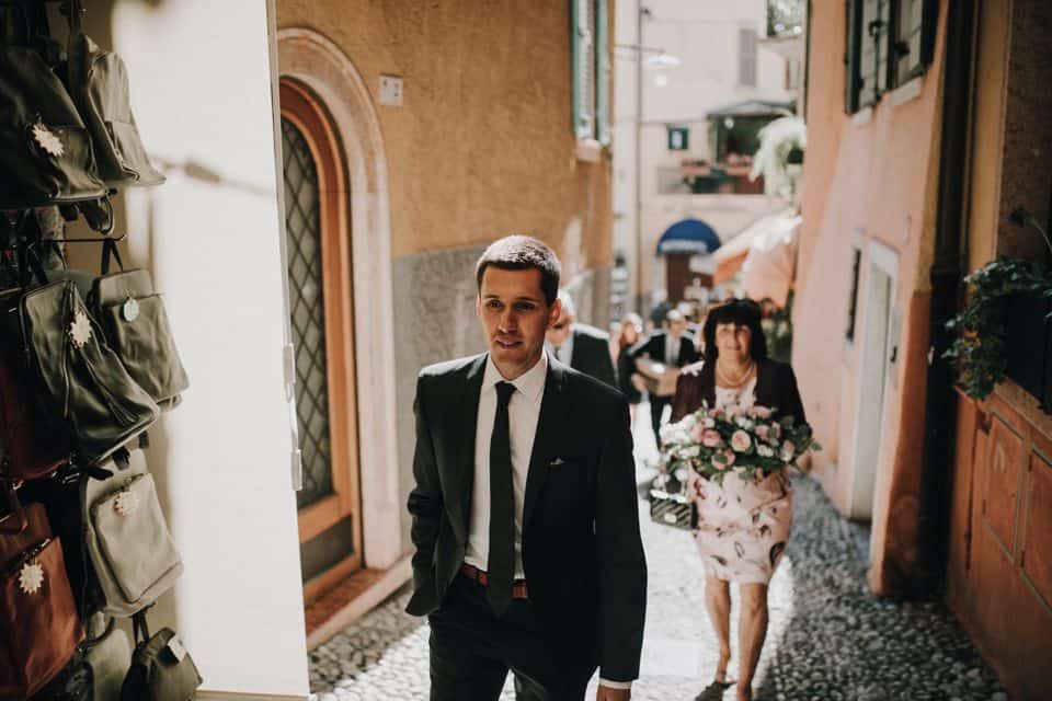 Eleganter Bräutigam in Anzug auf enger italienischer Gasse in Tirol, Österreich, bei einer Hochzeit.