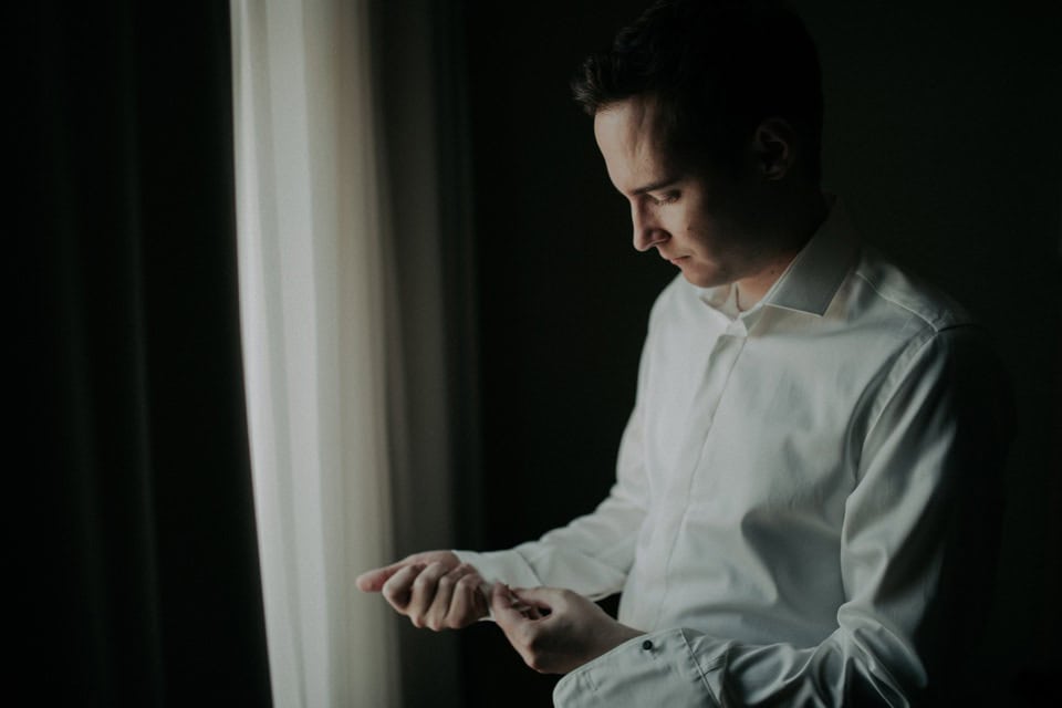 Mann in weißem Hemd bereitet sich auf den Hochzeitstag vor, elegantes Hochzeitsfoto aus Tirol, Österreich.