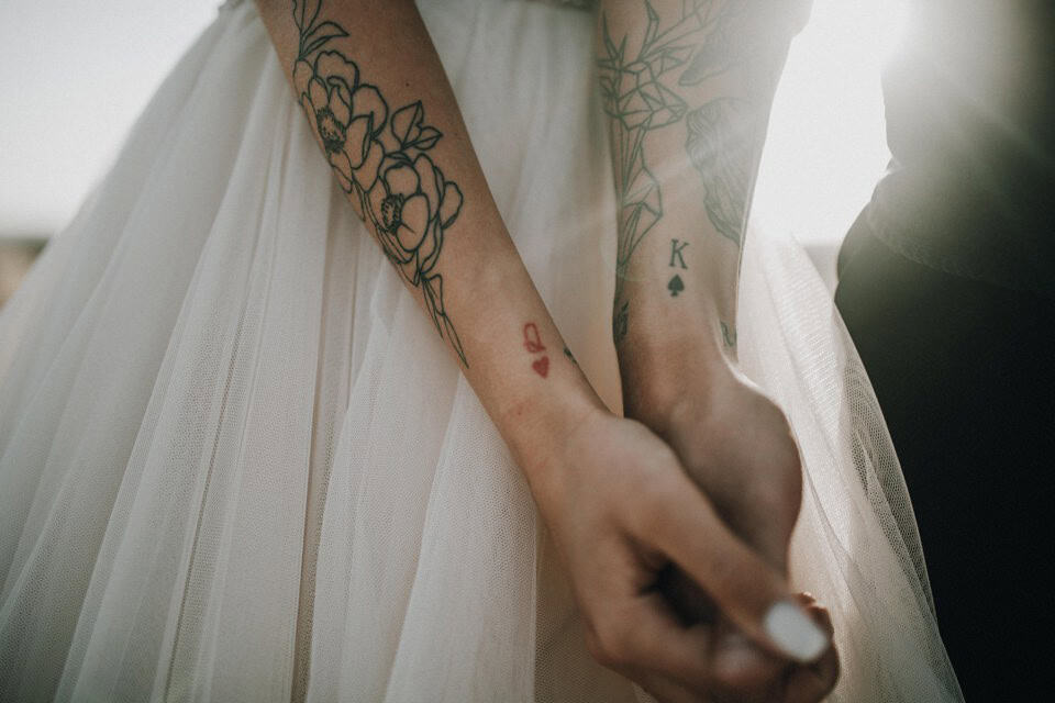 Tattoo-Händen eines Brautpaares bei Hochzeitszeremonie in Tirol, Österreich.