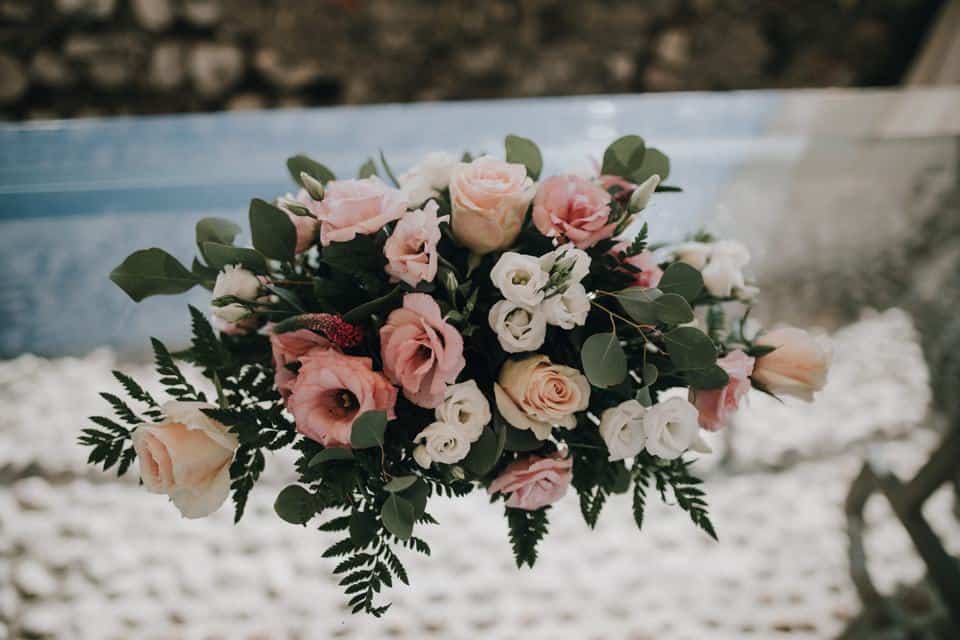 Blumendekoration mit rosa und weißen Blumen für Hochzeitsfeier auf Holzbank, romantische Atmosphäre.