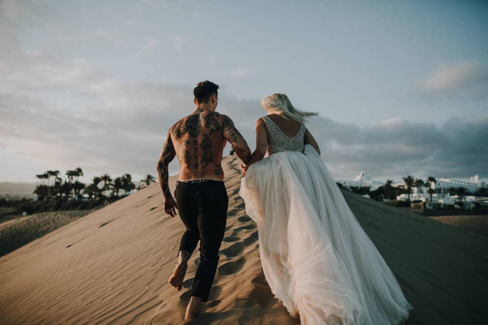 Hochzeitspaar läuft auf Sanddüne am Strand bei Sonnenuntergang in Tirol, Österreich, international.