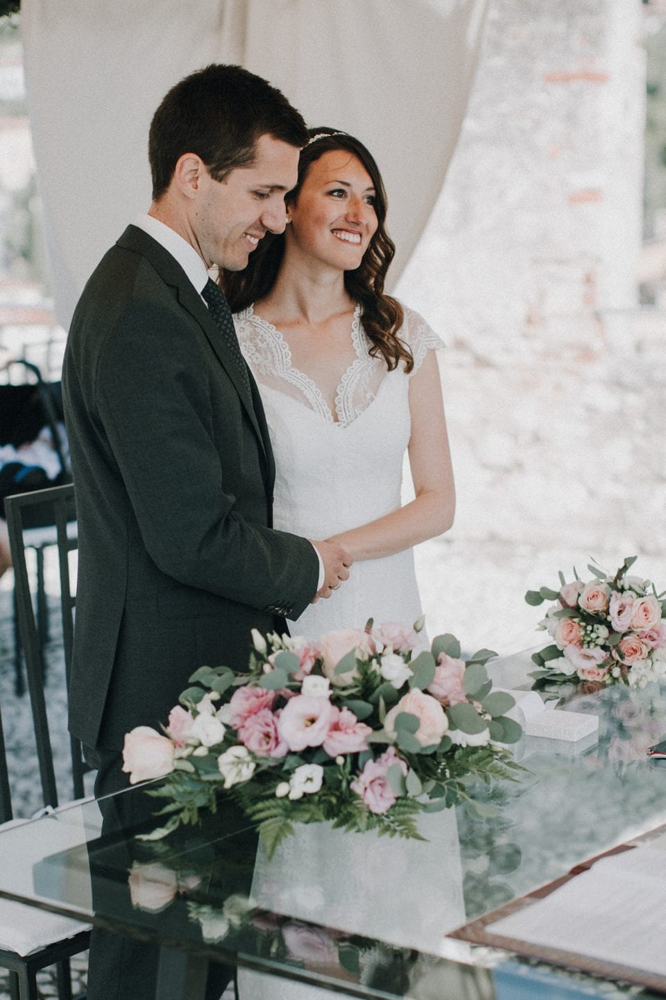 Hochzeitspaar bei Trauung mit Blumenarrangements und eleganter Kleidung in Tirol, Österreich.