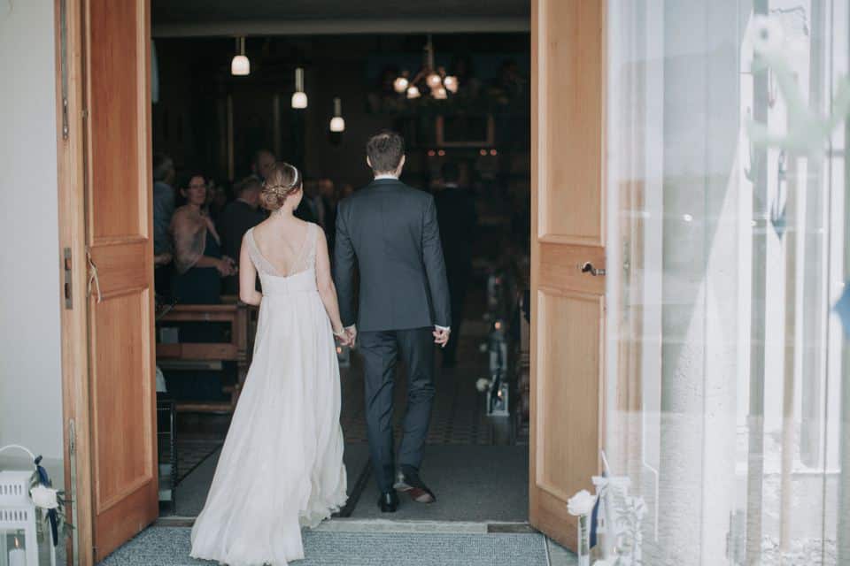 Hochzeitspaar betritt durch offene Holztüren im Gastraum Tirol Österreich.