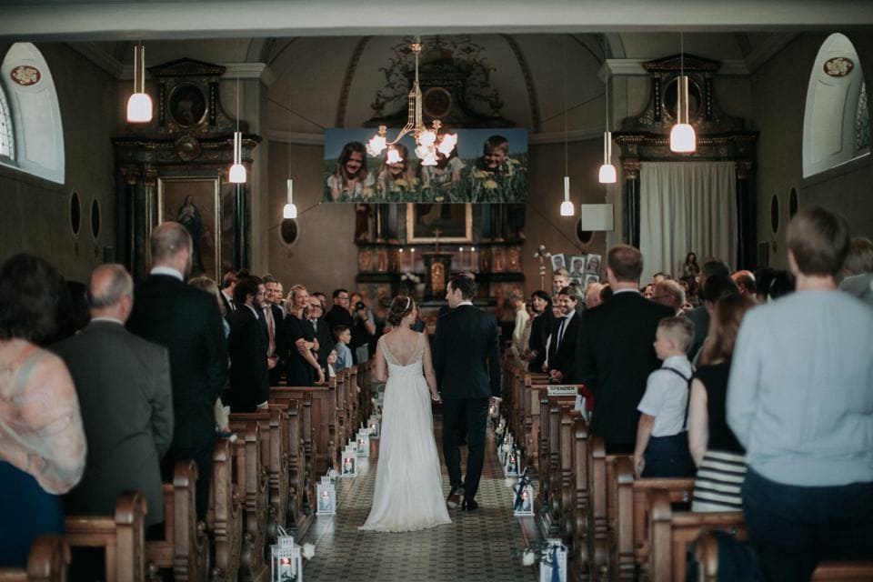 Hochzeitsreportage in einer Kirche in Tirol, Österreich, mit glücklichem Brautpaar und Gästeschar.