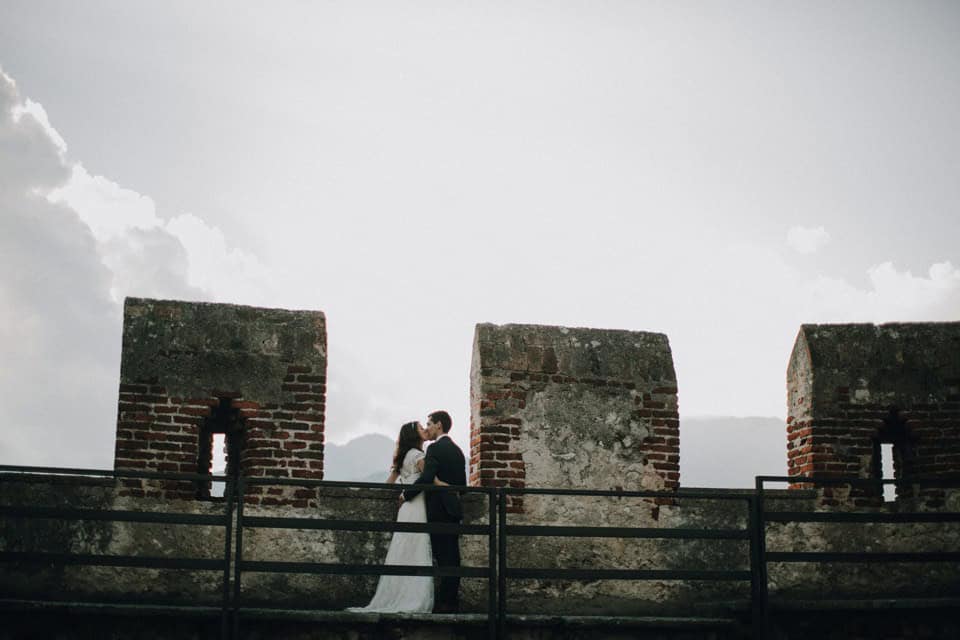 Hochzeitspaar auf alter Burgmauer bei Sonnenuntergang in Tirol, Österreich.