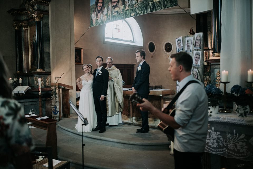 Hochzeitszeremonie in einer Kirche mit Musiker und Brautpaar, festliche Atmosphäre, emotionaler Moment, Tirol Österreich, internationale Hochzeitsfotografie.