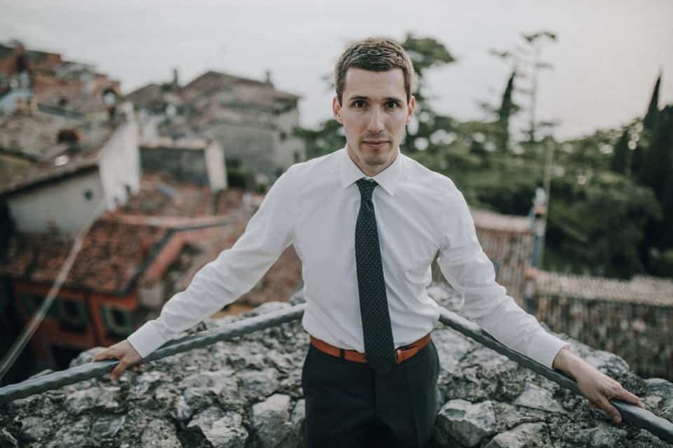 Beeindruckender junger mann auf balkon mit stadtblick, formale kleidung, gelungene hochzeitsaufnahme in Tirol.