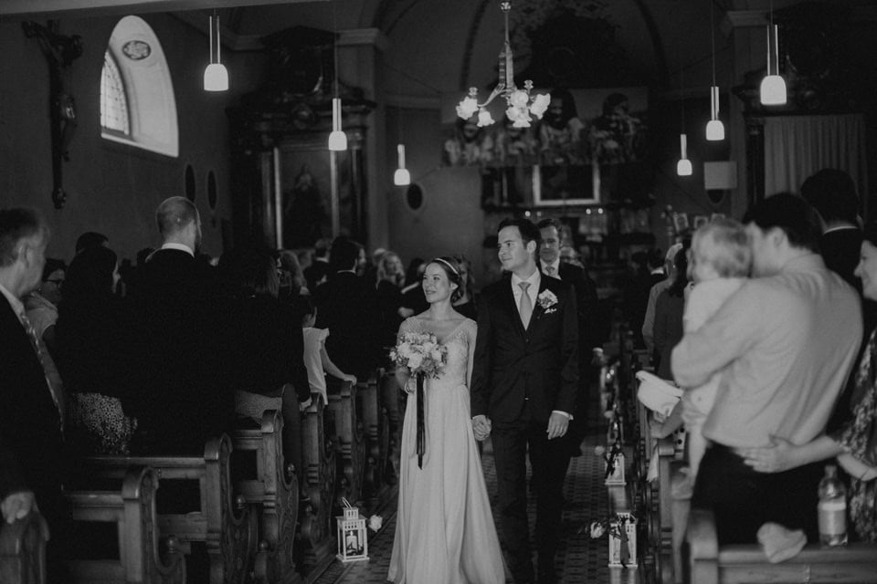 Hochzeitspaar beim Ja-Wort in einer prachtvollen Kirche, festliche Atmosphäre und liebevolle Blicke.