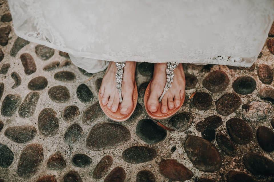 Schuhe einer braut mit steinen auf dem boden, Strandhochzeit, besondere hochzeitsdetails.