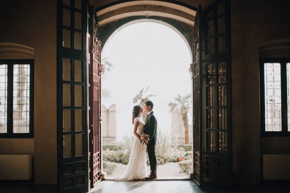 Verliebtes Brautpaar beim Ja-Wort in einer lichtdurchfluteten Kapelle in Tirol, Österreich, mit Blick ins Freie.