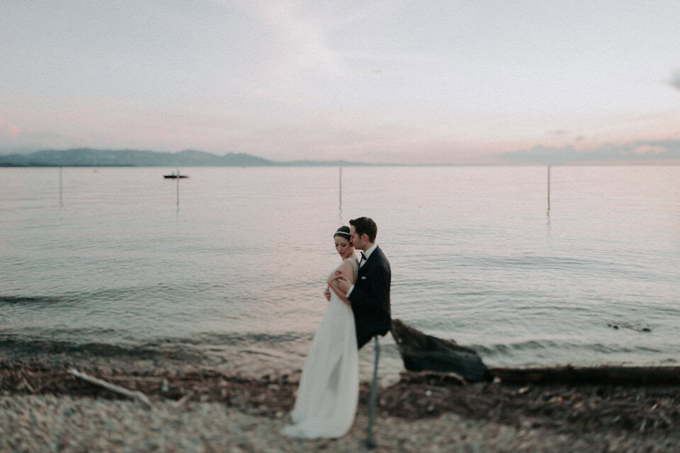 Verliebtes Hochzeitspaar am Seeufer bei Sonnenuntergang in Tirol.