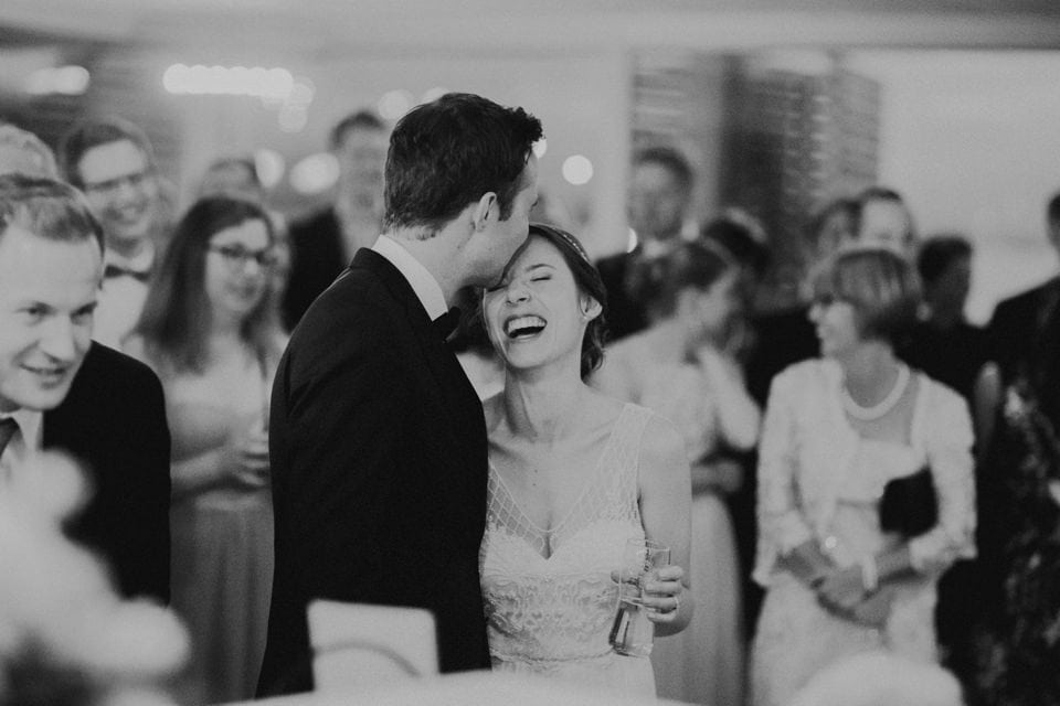 Freude bei hochzeit, lachendes brautpaar mit gästen beim fest gesellschaft, schwarze und weiße hochzeitsfotos von forma photography.