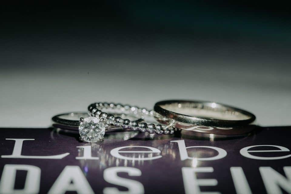 Eheringe und Verlobungsring auf einem Buch mit dem Wort "Liebe" in Großbuchstaben.