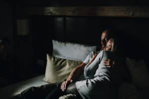 Romantisches Pärchen in einer liebevollen Umarmung im dunklen Schlafzimmer.