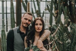 Ein verliebtes Brautpaar in einem Gewächshaus mit Kakteen und tropischen Pflanzen.