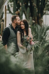 Naturromantische Hochzeitsfotos von einem Brautpaar mit Blumenstrauß in tropischer Umgebung.