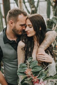 Nächtliches Hochzeitsporträt eines Paares in einem tropischen Gewächshaus, romantische Atmosphäre, Intimität und Liebe.