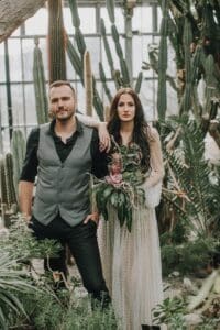 Elegantes Brautpaar in einem Gewächshaus mit Kakteen und tropischen Pflanzen, stilvoll für eine Hochzeitsfotografie.