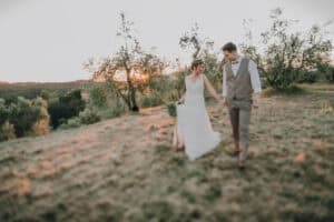 Hochzeitsfotograf Tirol, Brautpaar im Sonnenuntergang auf dem Feld, emotionale Hochzeitsfotos, natürliche Landschaftsaufnahmen, internationale Hochzeitsfotografie.