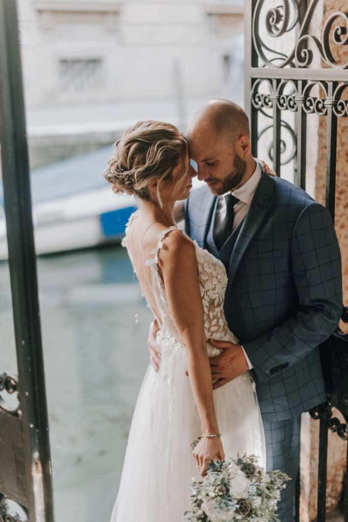 Hochzeitspaar in inniger Umarmung am Wasser in Tirol, romantisches Hochzeitsfoto.