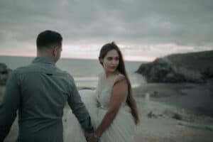 Trauriges Brautpaar am Strand bei Sonnenuntergang, Hochzeitsfotos in Tirol, emotionales Hochzeitsbild, Natürliche Hochzeitsfotografie, internationale Hochzeitsfotografen.