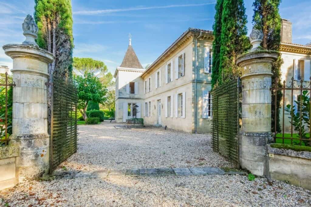 Prächtiges chateau in tirol mit grünen bäumen und geschmiedetem tor.