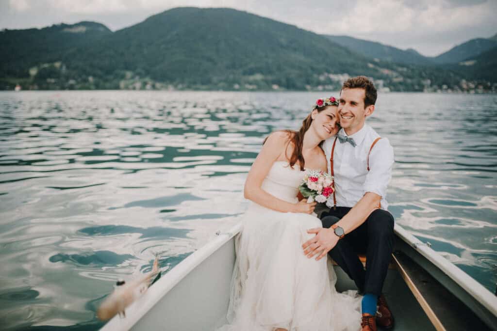 Trauung am wunderschönen Wolfgangsee, verliebtes Brautpaar in einem Ruderboot in Tirol, Österreich, internationales Hochzeitsshooting.