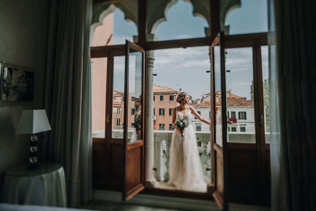 Hochzeitsshooting in einem venezianischen Fenster mit Blick auf historische Gebäude in Venedig, Italien.