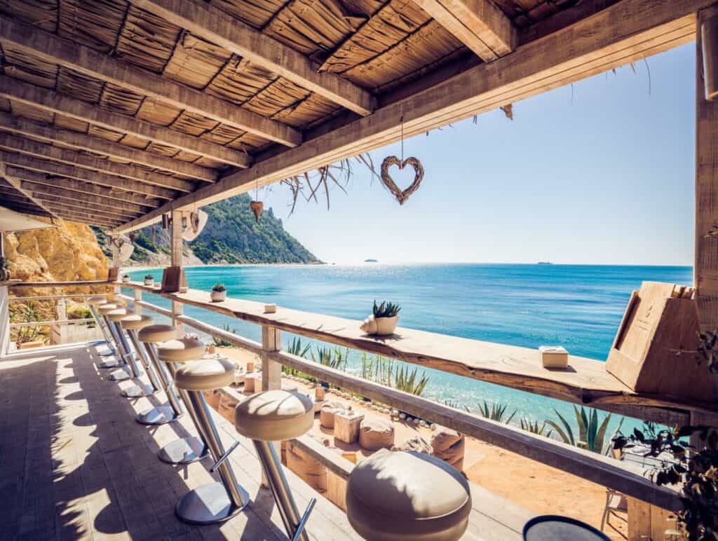 Sonniges Strandcafé mit Blick aufs Meer und Herz-Dekorationen, romantische Kulisse für Hochzeiten.
