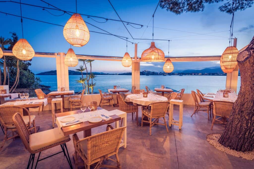 Gemütliche Strandterrasse mit festlicher Beleuchtung und Meerblick bei Sonnenuntergang.