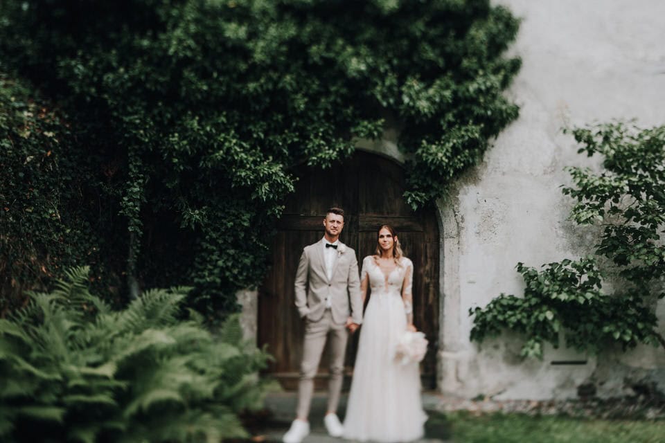 Hochzeitspaar in natürlicher Umgebung vor altem Tor in Tirol, Österreich.