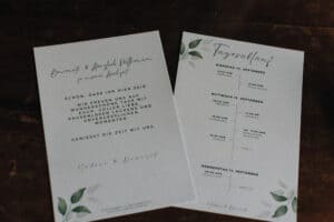 Elegante Hochzeitszeitplan und Willkommenskarte mit grünen Blättern, perfekt für kreative Hochzeiten in Tirol.
