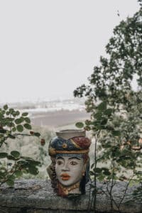 Ostergefäß in Form einer Frau mit buntem Schmuck vor Naturkulisse, ideal für kreative Hochzeitsdekorationen.