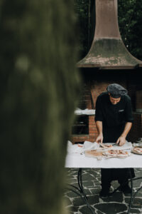 Fleischzubereitung im Außenbereich bei einer Hochzeit, professioneller Koch beim Schneiden.