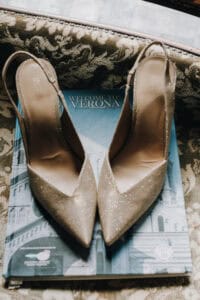 Elegante goldene Hochzeitsschuhe auf einem Reiseführer mit Veronas Wahrzeichen.
