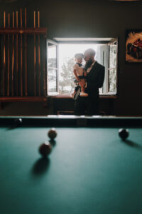 Hochzeitsfotograf Tirol, emotionales Bild eines Mannes mit Kind bei Hochzeit, natürliche Lichtstimmung.