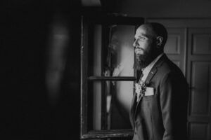 Mohr mit Bart im Anzug blickt nach rechts in einem schwarzen und weißen Hochzeitsfoto.