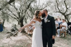 Hochzeitspaar beim Kuss unter blühenden Bäumen, romantische Außentrauung, Hochzeitsfotograf Tirol Österreich, internationale Hochzeitsfotografie.