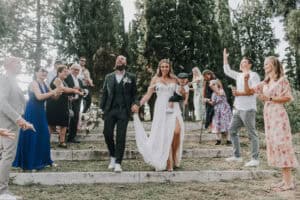 Fröhliches Brautpaar mit Gästen bei einer outdoor Hochzeit in Tirol, Österreich.