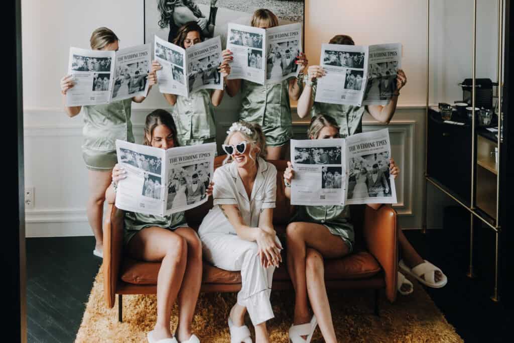 Braut mit Brautjungfern im Pyjama liest Hochzeitszeitung.