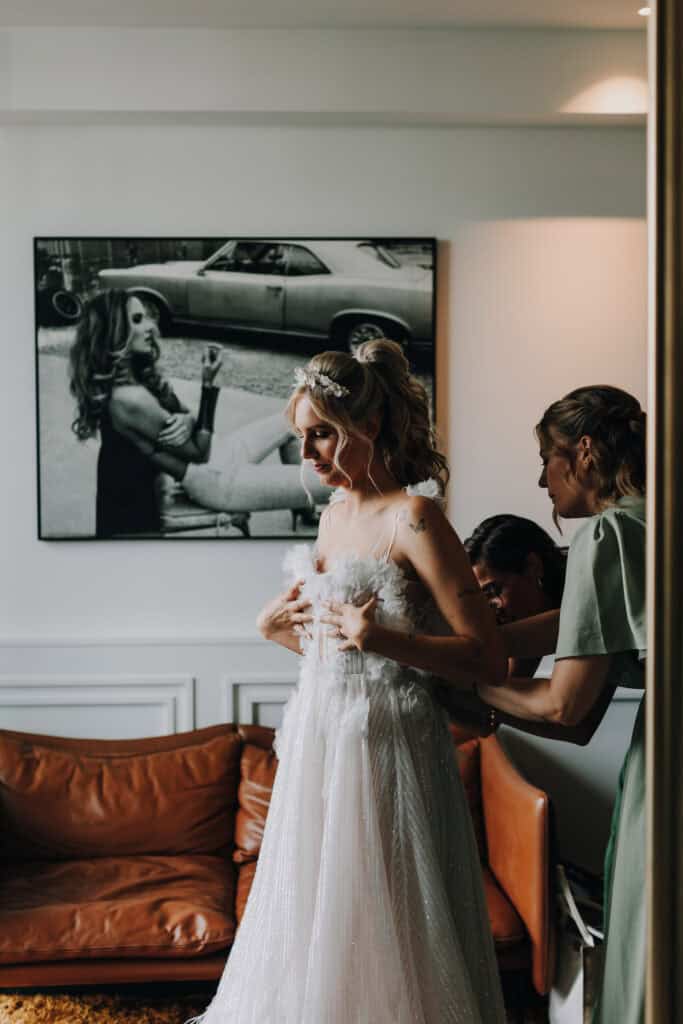 Braut wird im Brautkleid geholfen. Hochzeitsfotograf München.