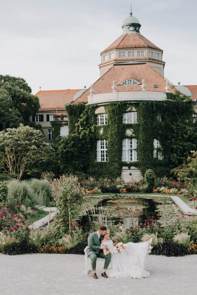 Brautpaar sitzt vor dem Botanischen Garten München. Hochzeit in München. Romantische Hochzeit.