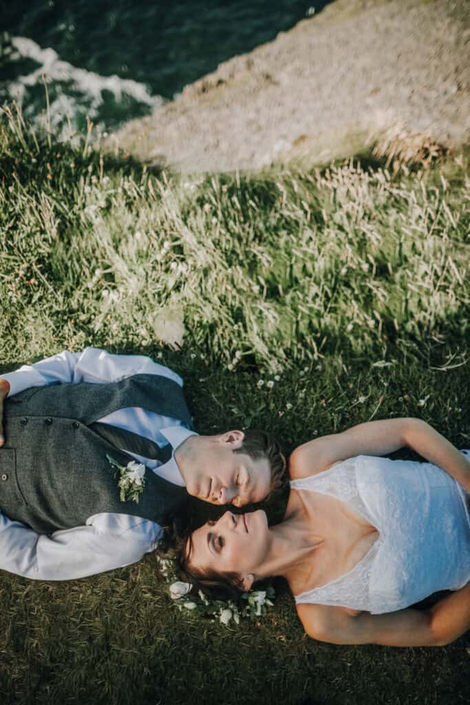 Brautpaar liegt im Gras an der Küste Irlands. Hochzeitsfotograf Irland.